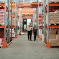 Pemilik usaha sedang merapikan stok barang dagangan berupa mie instan di rak toko kelontong