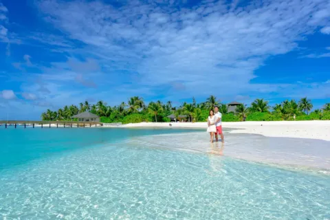 Pasangan menikmati pemandangan indah di destinasi honeymoon romantis tepi pantai