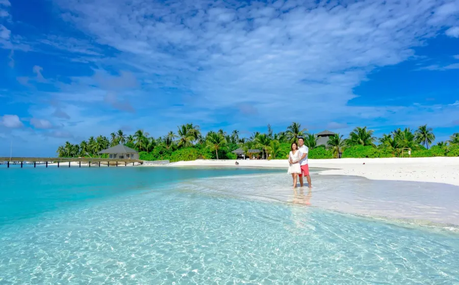 Pasangan menikmati pemandangan indah di destinasi honeymoon romantis tepi pantai
