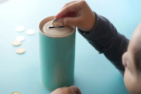 Orang tua sedang mengajarkan anak tentang uang dan menabung dengan celengan