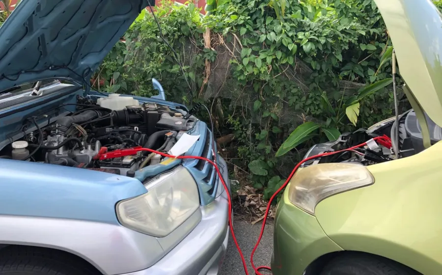 Seorang pengemudi sedang memeriksa mesin untuk mengatasi mobil sulit dinyalakan di pinggir jalan