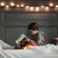 Orang tua membacakan buku cerita bergambar bersama anak di atas karpet rumah untuk membangun kebiasaan membaca sejak dini