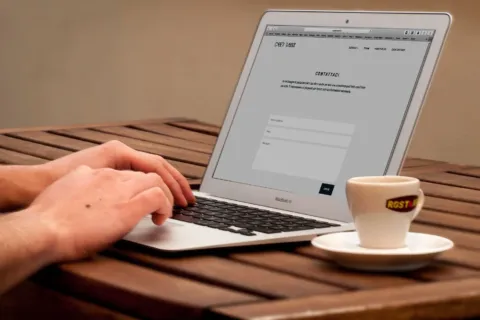 Pengusaha sedang menerapkan cara membuat website bisnis sendiri melalui laptop di meja kerja