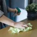 Membersihkan meja rumah dari debu menggunakan kain mikrofiber lembap