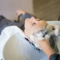 Seseorang sedang mengaplikasikan pembersih kulit kepala dalam panduan cara merawat rambut berketombe