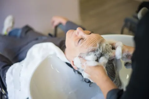 Seseorang sedang mengaplikasikan pembersih kulit kepala dalam panduan cara merawat rambut berketombe