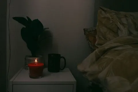 Suasana kamar tidur malam hari dengan lampu temaram hangat untuk mendukung ide pola tidur yang berkualitas