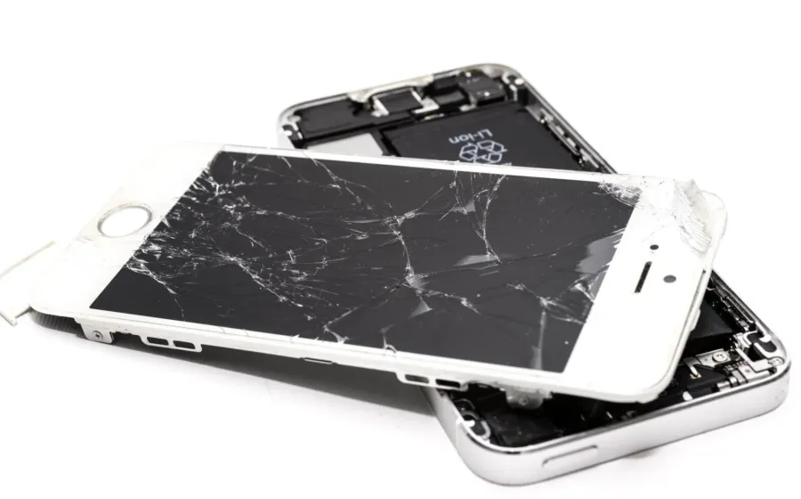 Tangan memegang smartphone dengan layar retak halus yang dipasangi pelindung kaca