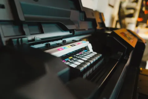 Seseorang sedang mencetak dokumen menggunakan printer ink tank hemat di meja kerja rumah